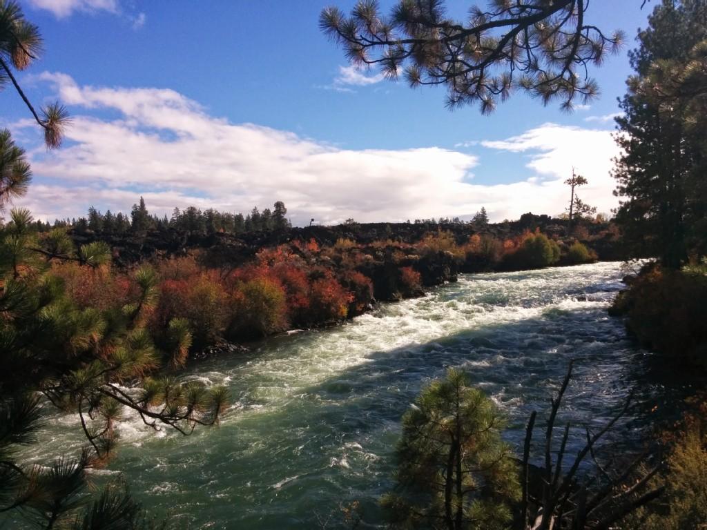 Rushing river with colorful autumn foliage and dark rock formations.