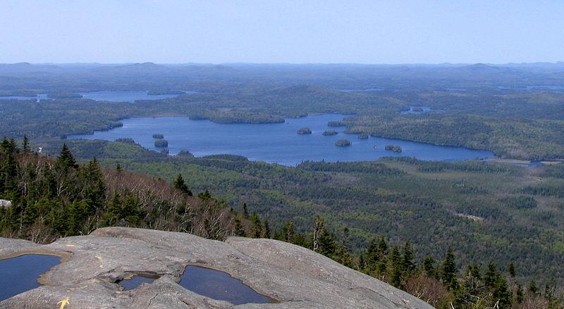 Expansive view of a large lake with islands surrounded by forests.