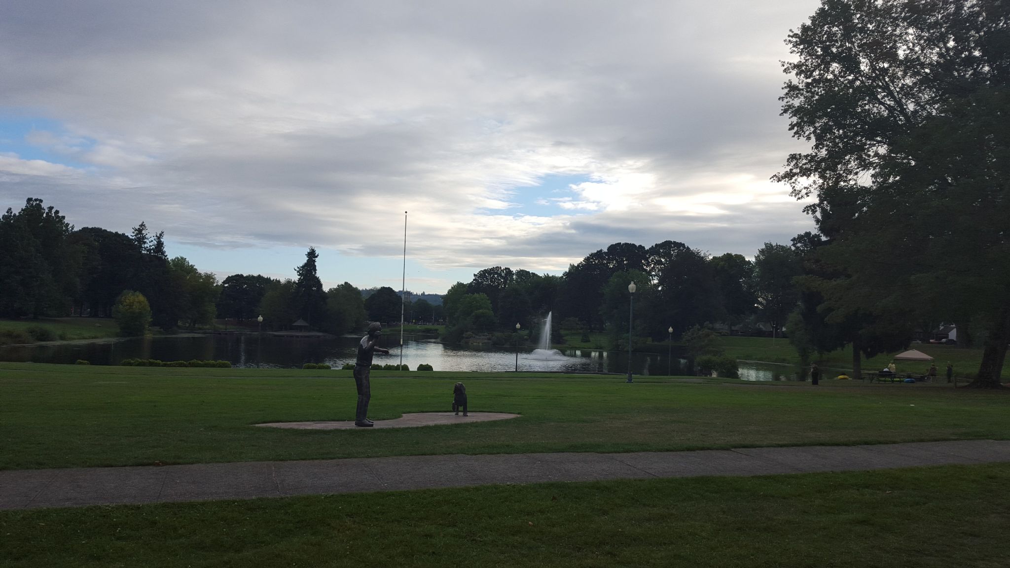 Park with a lake, fountain, and statues under an overcast sky. - Lake Sacajawea Park loop