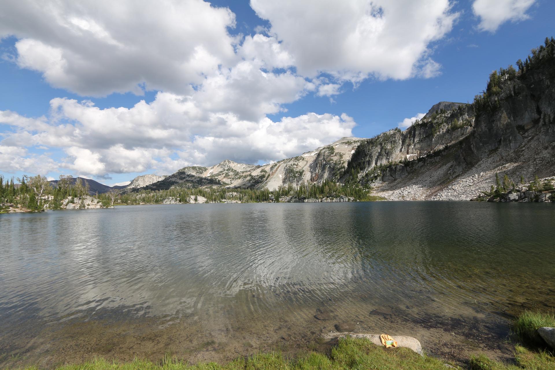 Sunny day over a clear mountain lake with rugged rocky slopes.