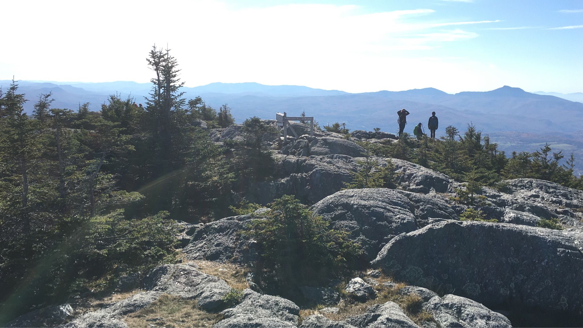 Three people on a rocky mountain summit overlooking distant peaks, bright day. - Mount Hunger Summit – Hogback Mountain loop from Barnes Hill