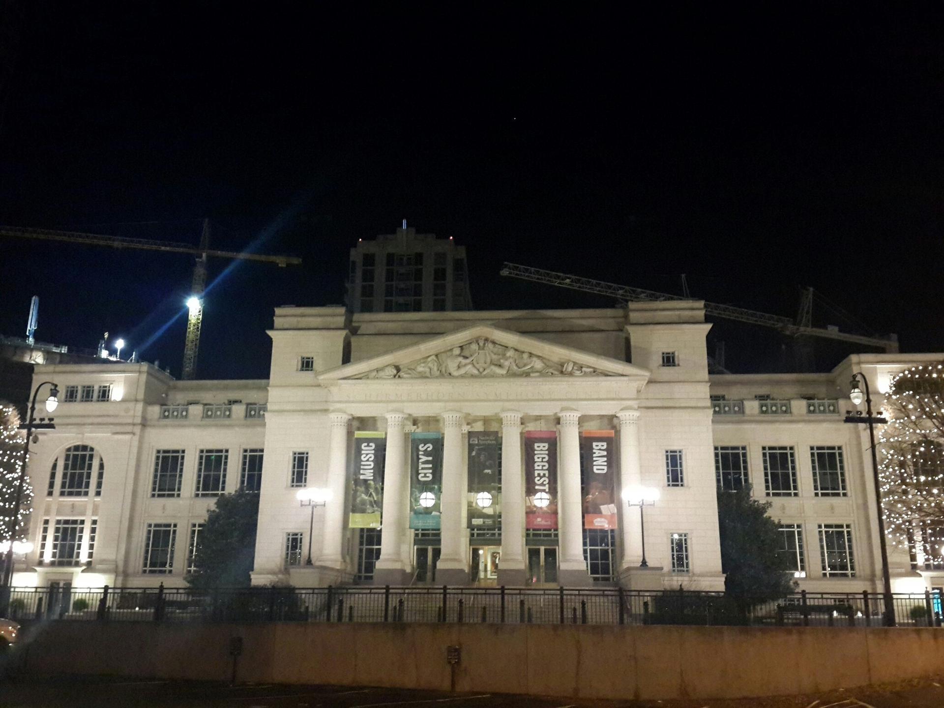 Grand white building with columns and banners, brightly lit at night.