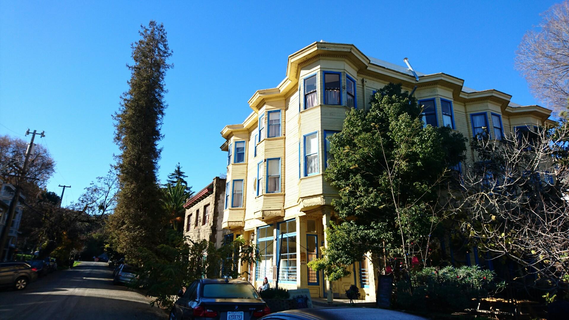 Ornate yellow building with bay windows on a sunny urban street.