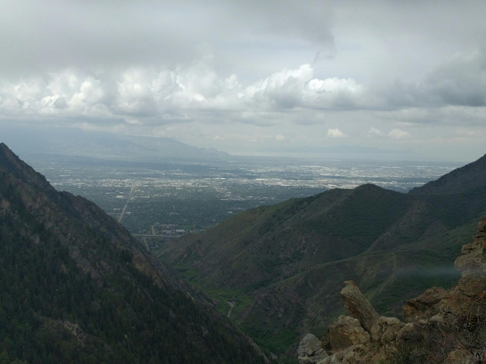 Panoramic view of a city in a valley between dark, cloudy mountains.