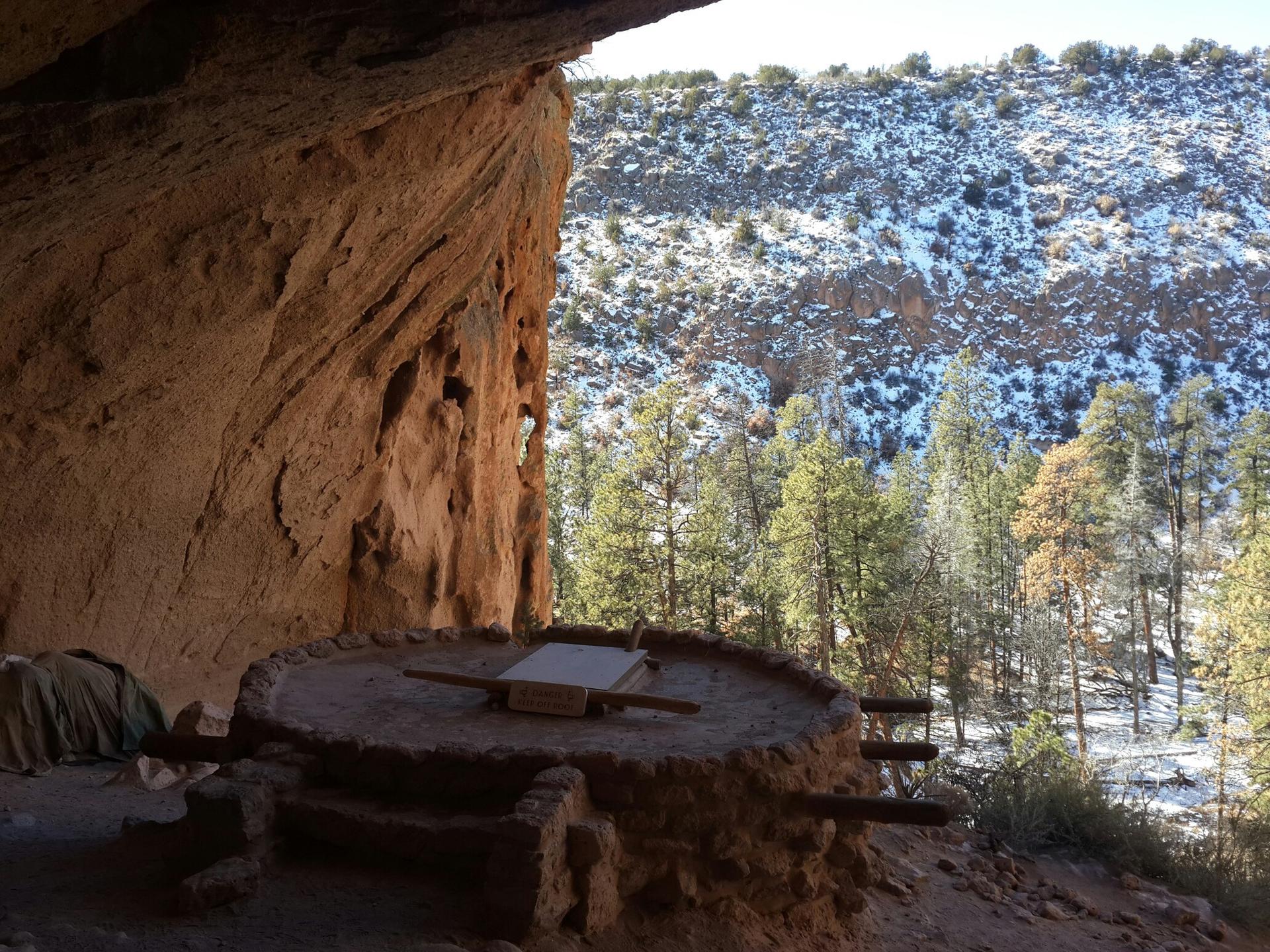 Ancient dwelling inside a cave, overlooking a snowy forest and mountain.