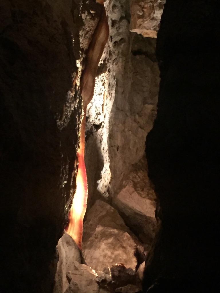 A glowing red cave formation illuminates a dark, narrow rocky passage.