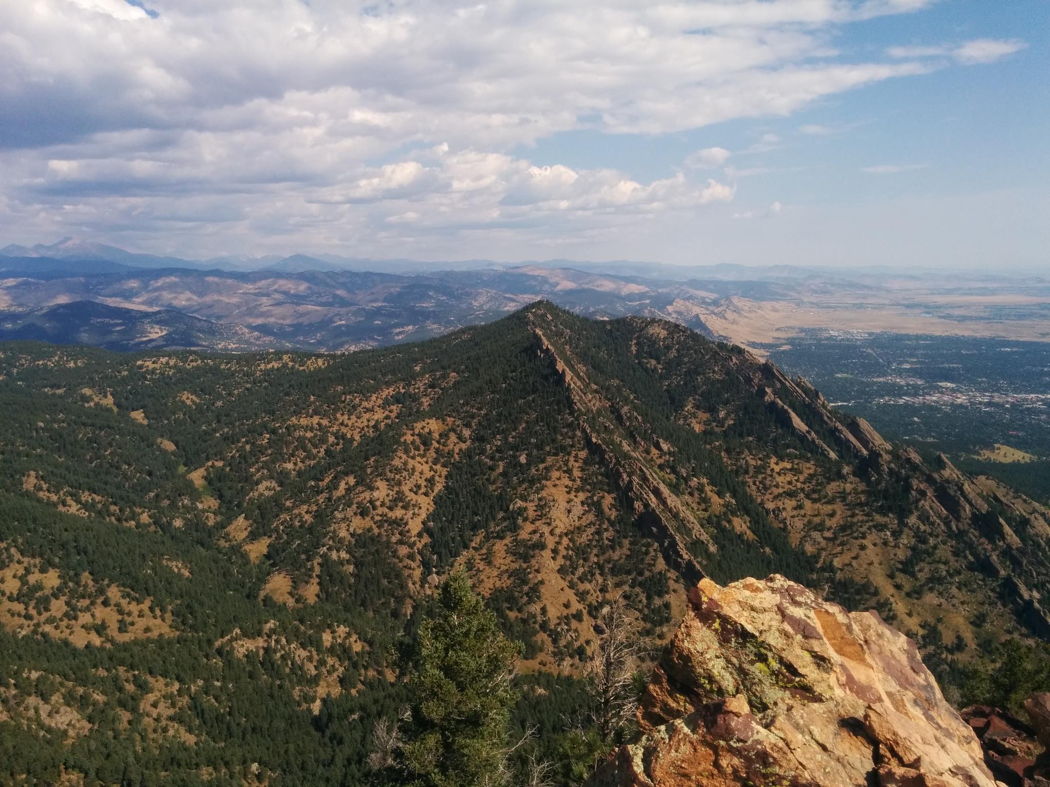 A mountain ridge covered in green trees, with a vast valley below.