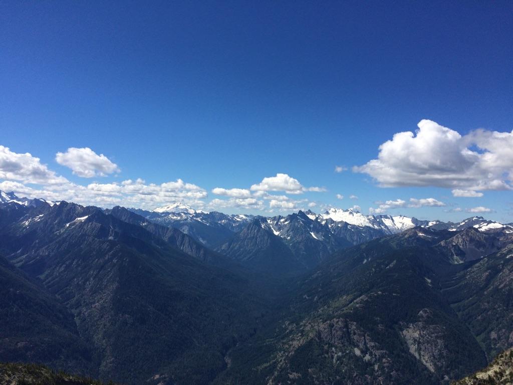 Panoramic view of vast mountain ranges with snow-capped peaks under blue sky.