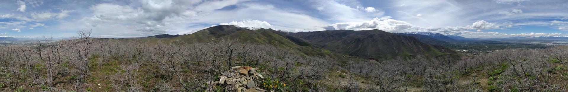 Panoramic view of a mountainous landscape with bare trees under a partly cloudy sky.