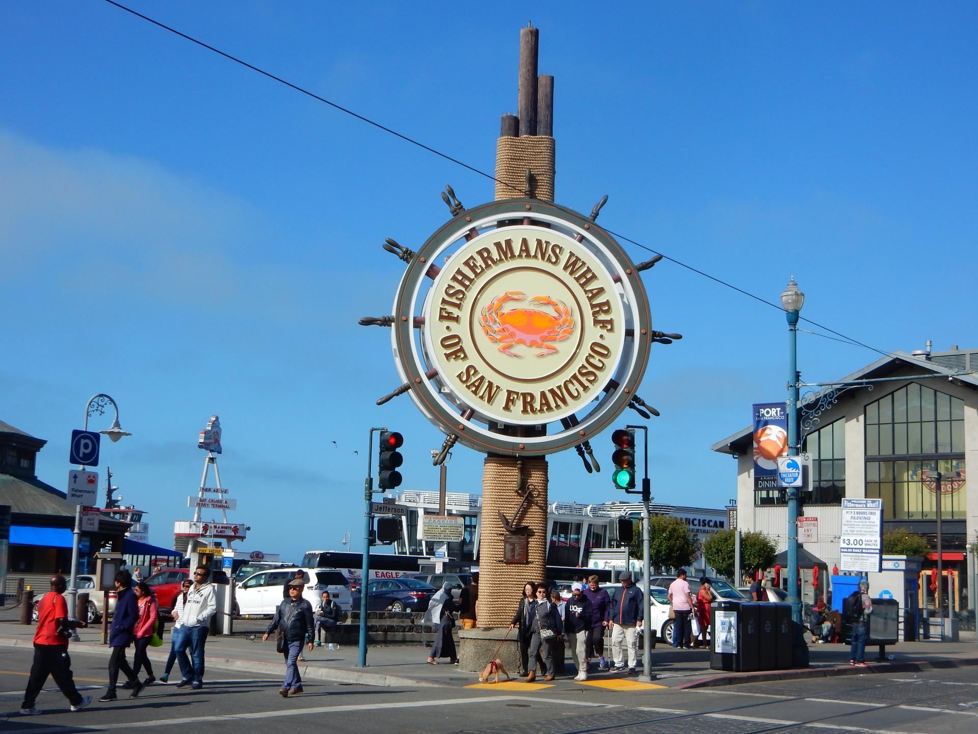 Large circular sign on a busy street with pedestrians under bright sun.