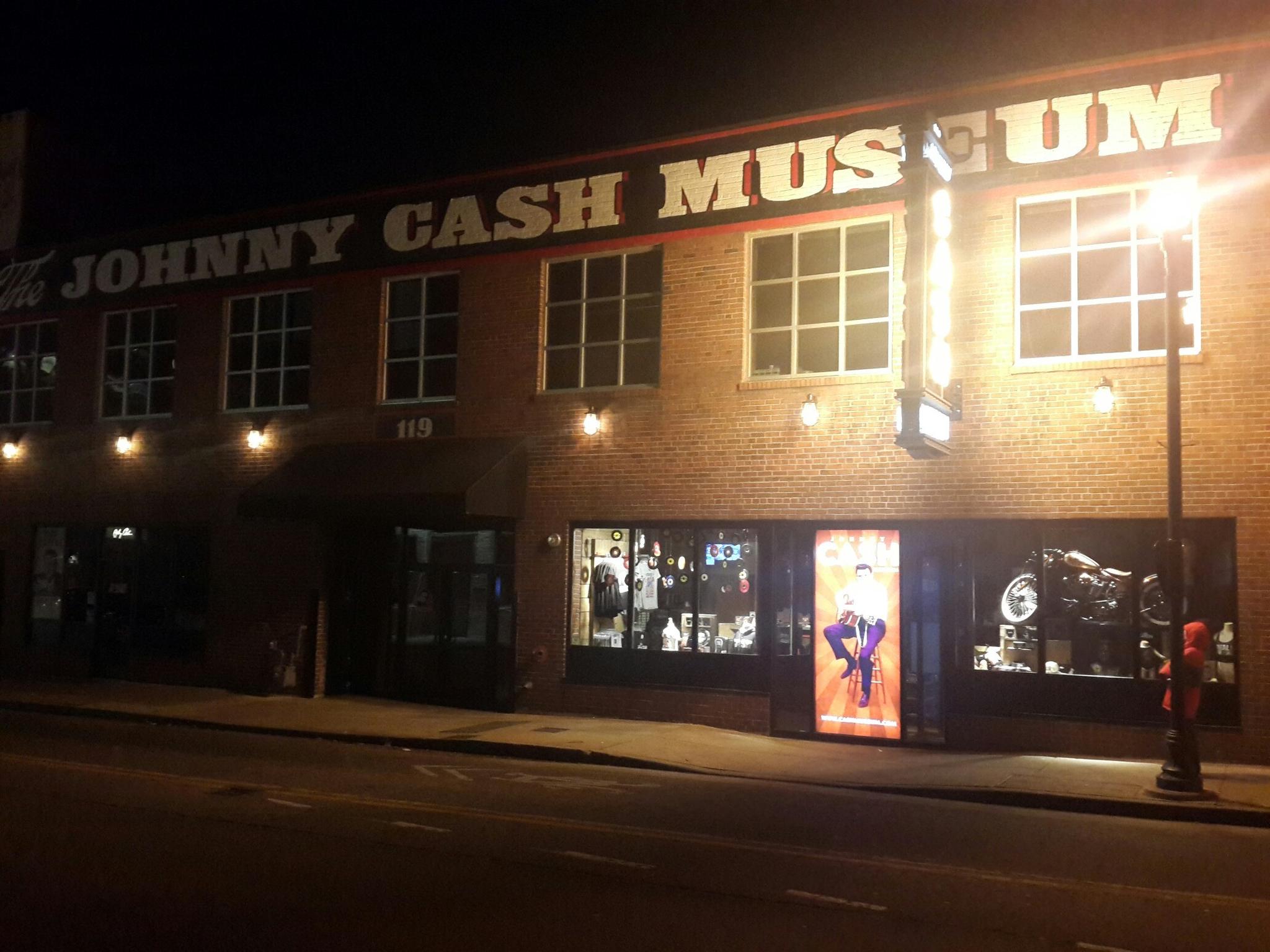 Illuminated brick building with a museum sign at night on an urban street.