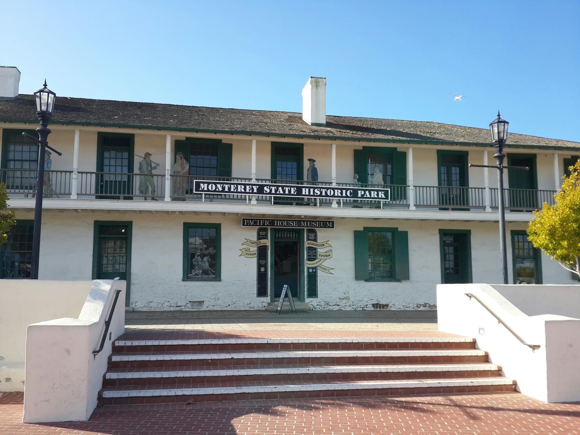 Historic white building with green shutters and balcony under a clear blue sky.