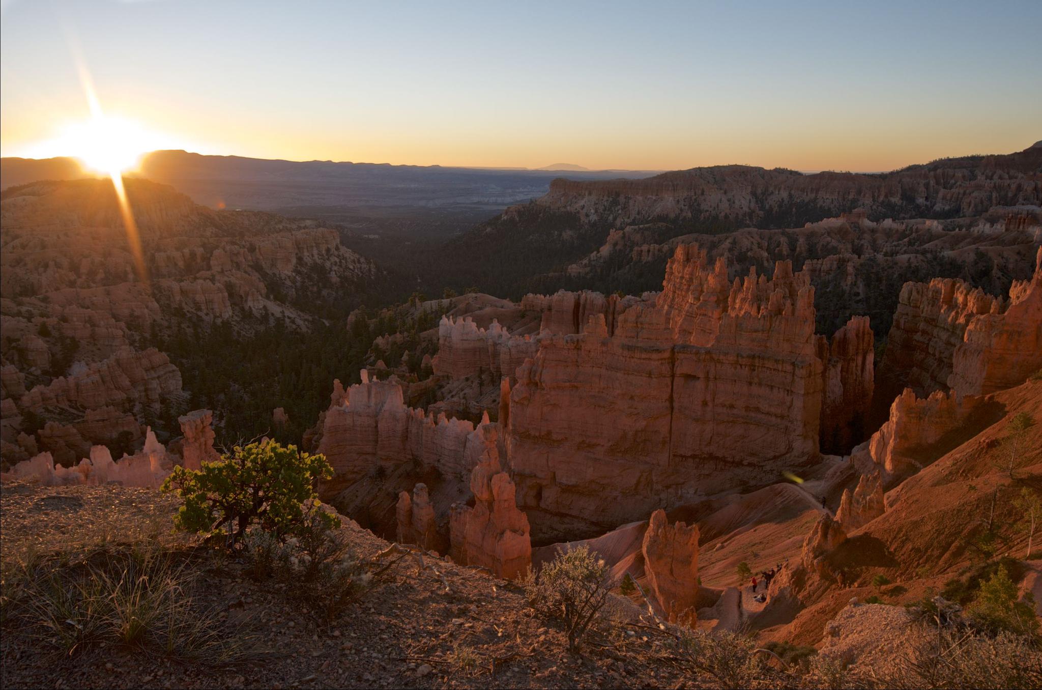 Sunset over a canyon filled with red rock formations, warm light.