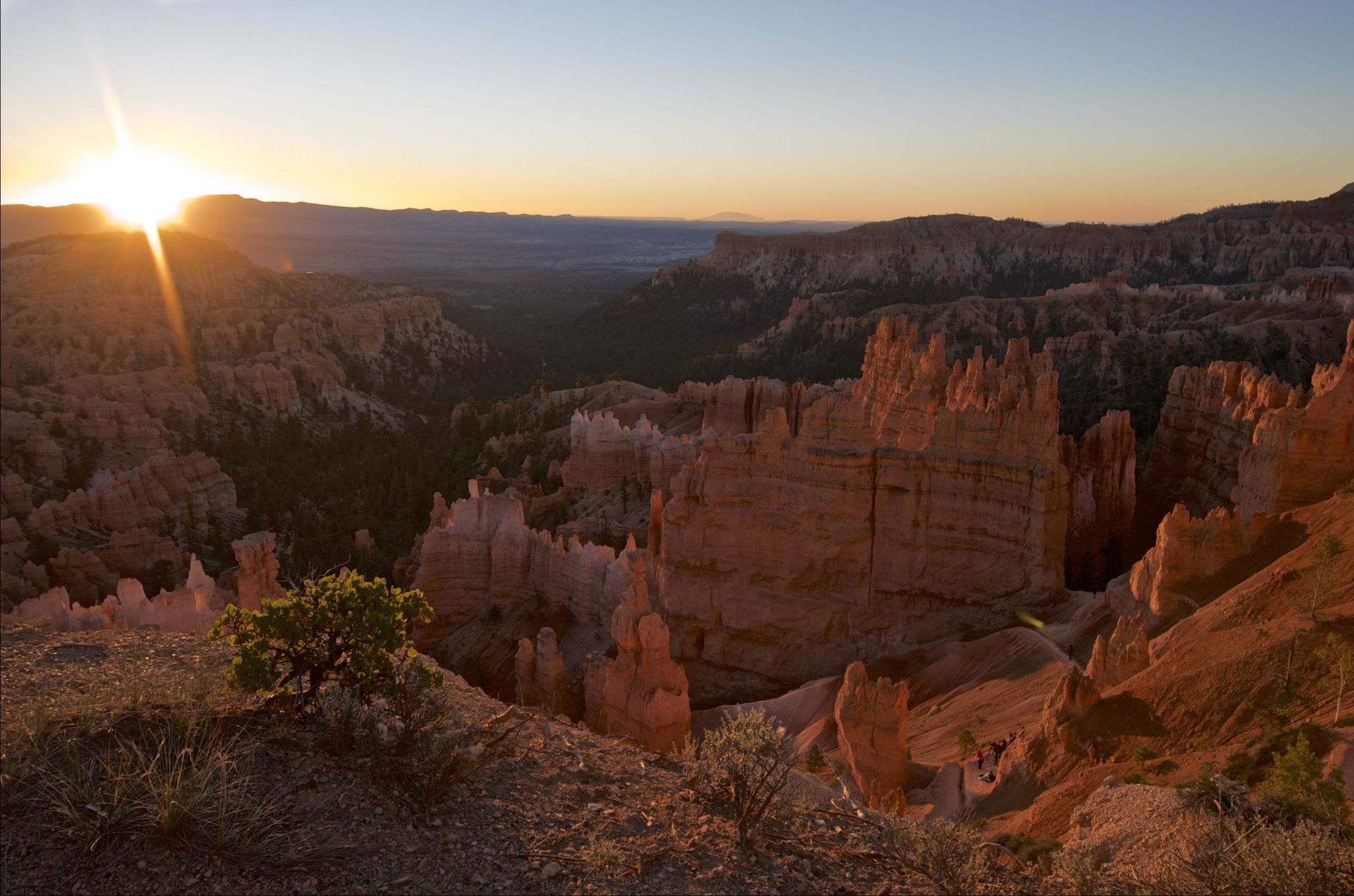 Sunset over a canyon filled with red rock formations, warm light. - Sunset Point – Queens Garden Trail loop from Bryce Canyon Lodge