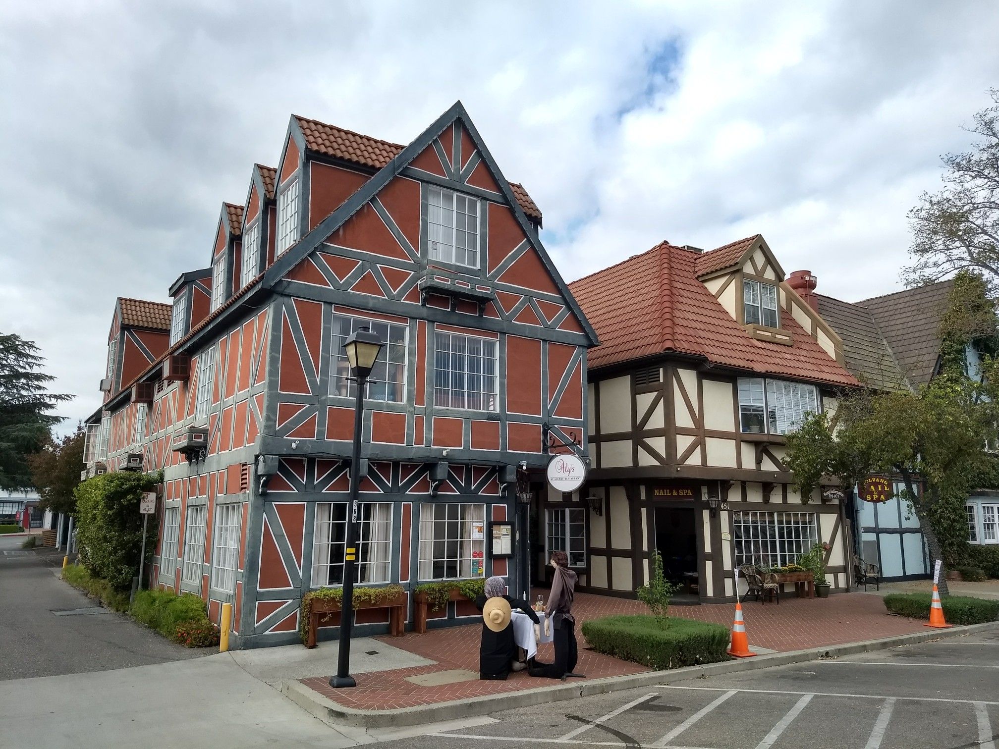 Ornate timber-framed buildings with people on the sidewalk under a cloudy sky. - Foxen Canyon & Drum Canyon Road loop