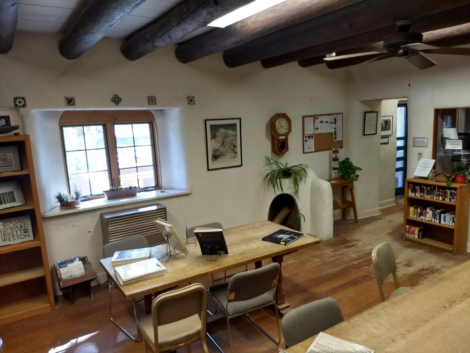 Cozy indoor room with wooden beams, tables, chairs, and a window.