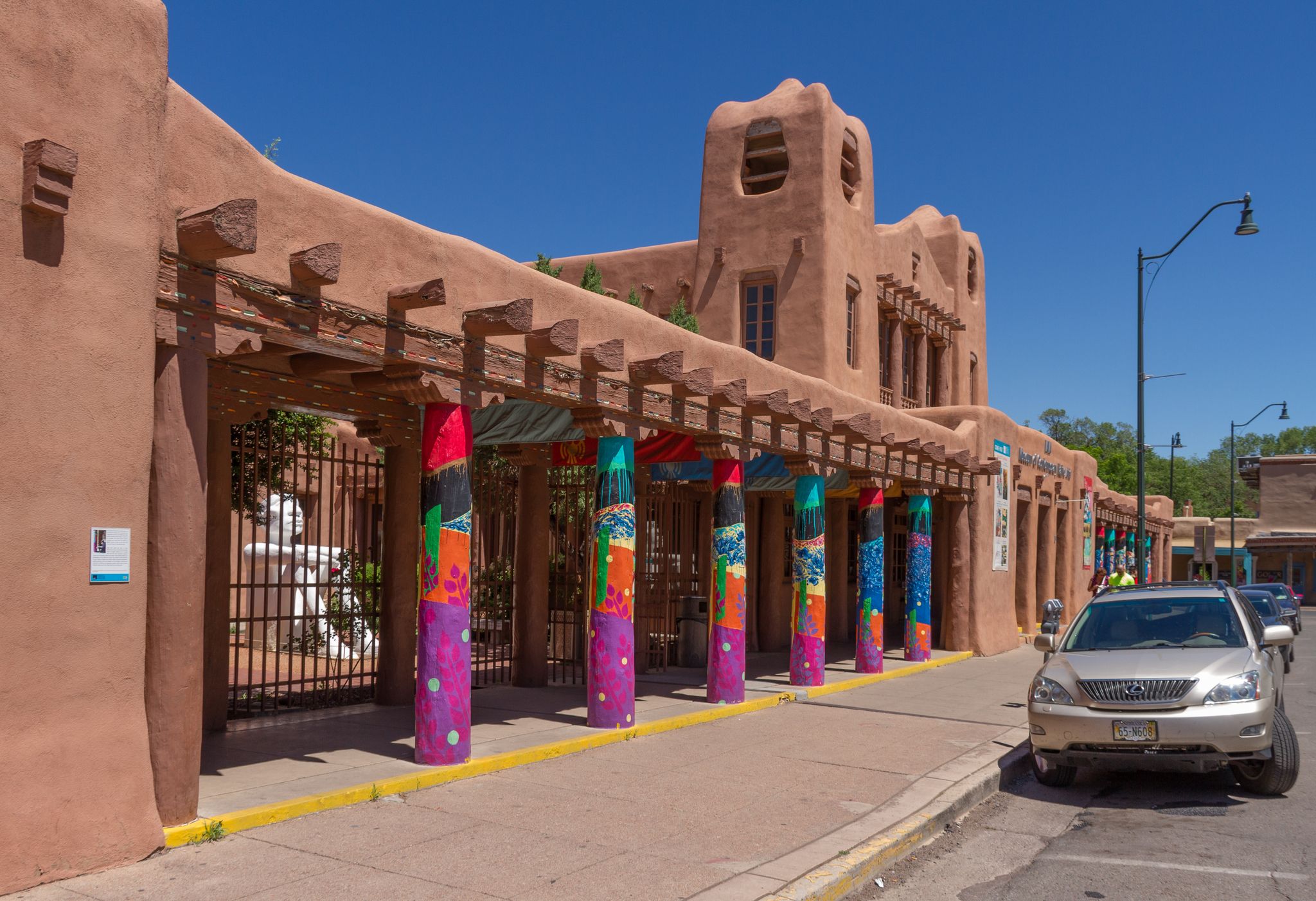 Adobe-style building with colorful pillars and a parked car under a bright blue sky. - Santa Fe River Trail – Santa Fe Plaza loop from Santa Fe
