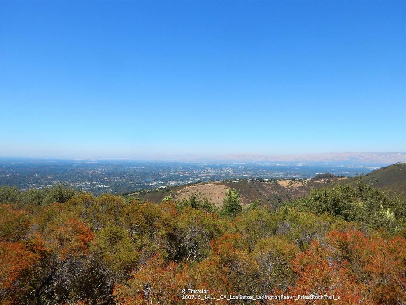 Panoramic view of a vast valley with urban areas under a clear blue sky.