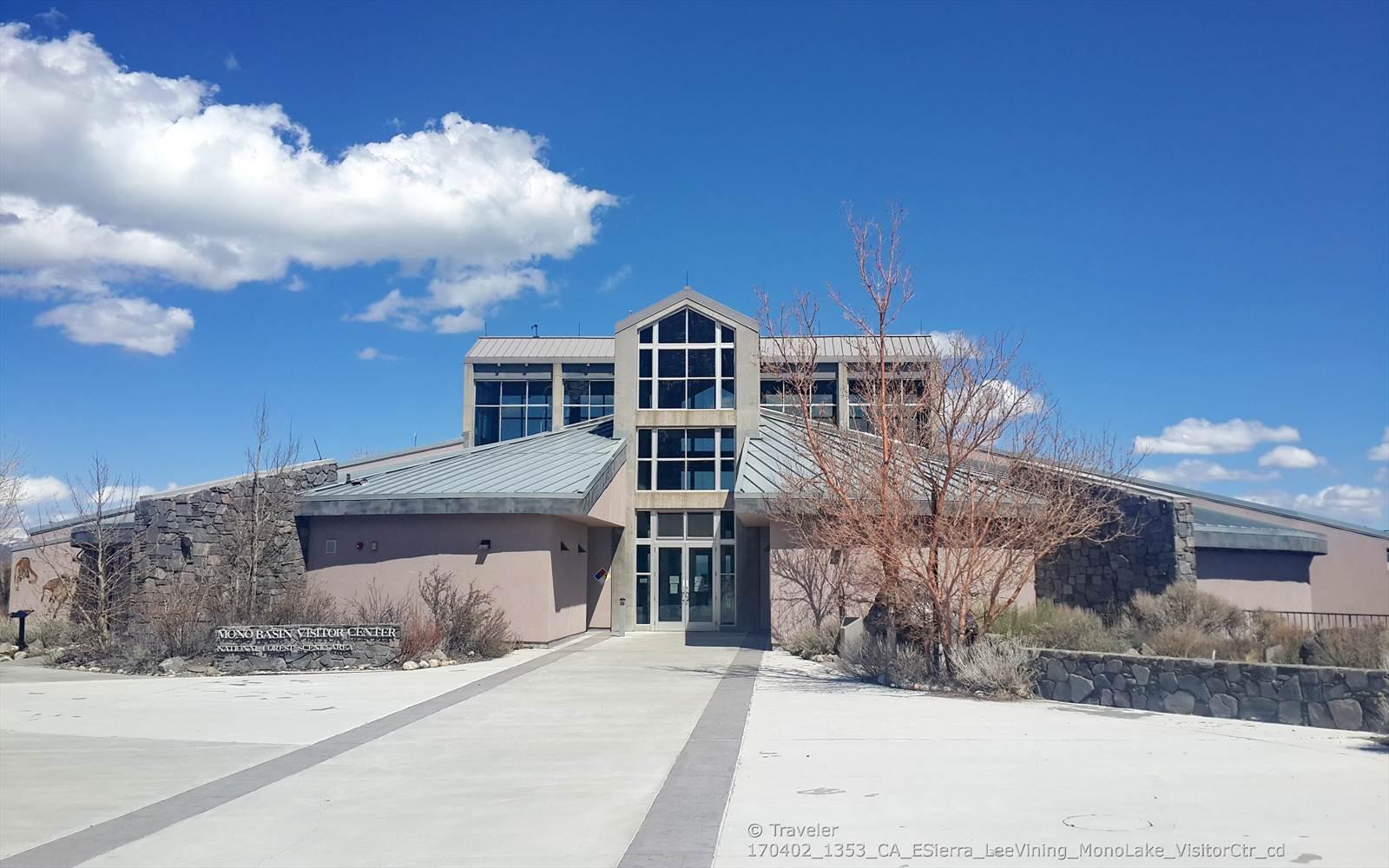 A modern building with large windows under a bright blue sky with white clouds.