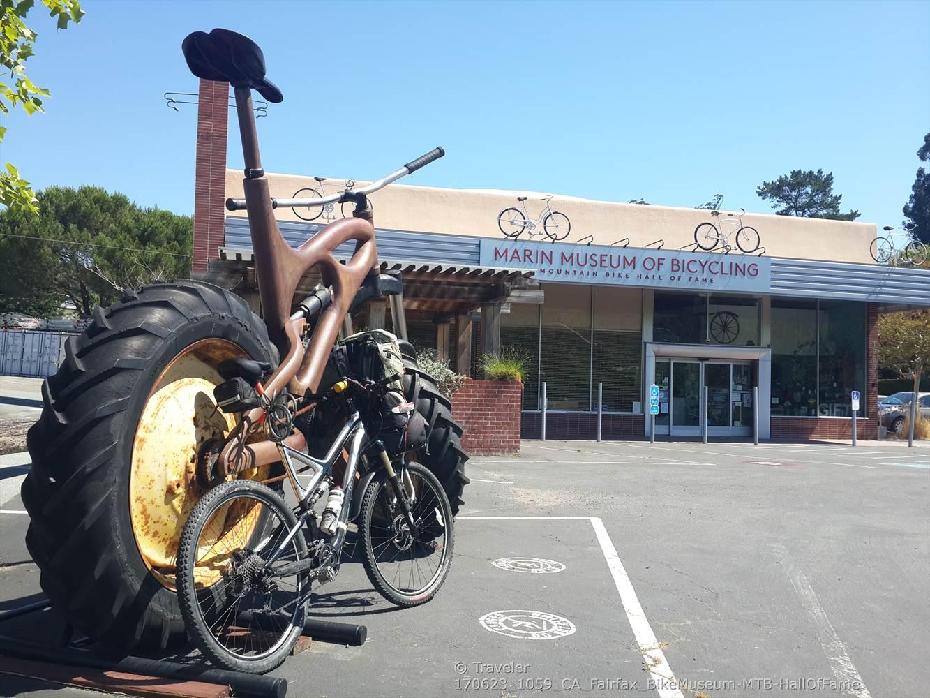Giant bicycle sculpture in front of a museum on a sunny day.