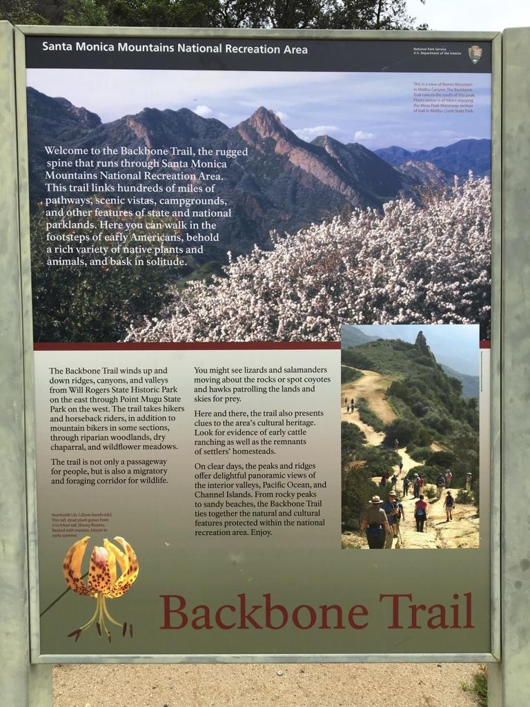 An information sign with text and images of mountains and hikers.