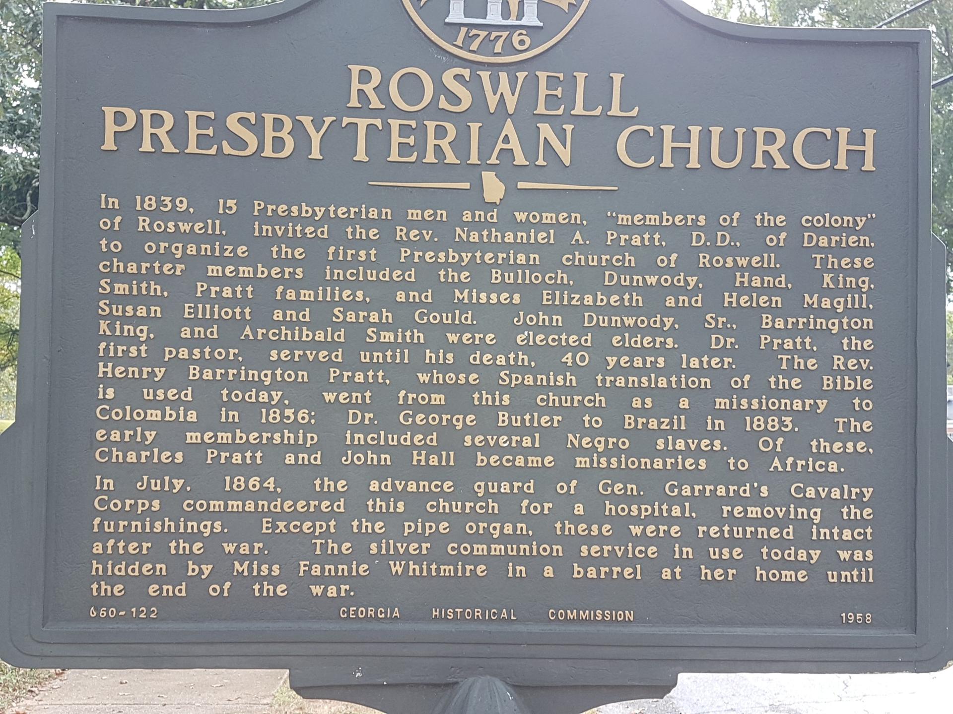 A close-up of a dark historical marker sign with gold text.