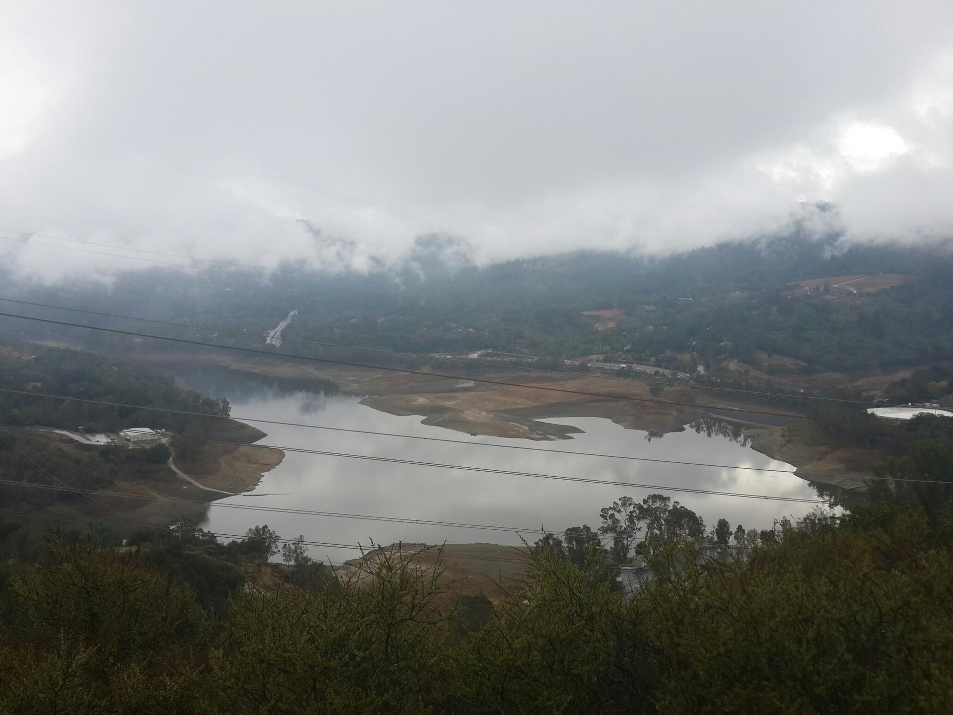 Overcast view of a lake and misty, forested hills.