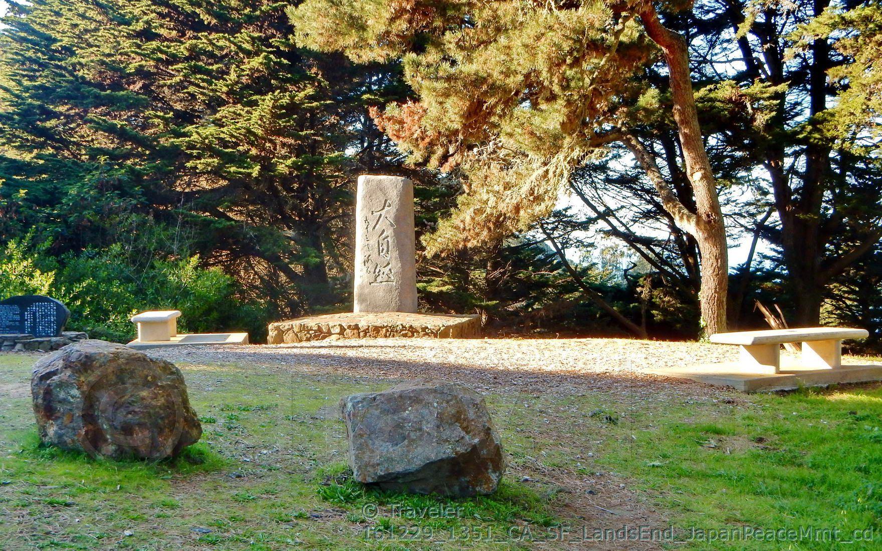 Stone monument and benches in a clearing surrounded by trees, golden light.