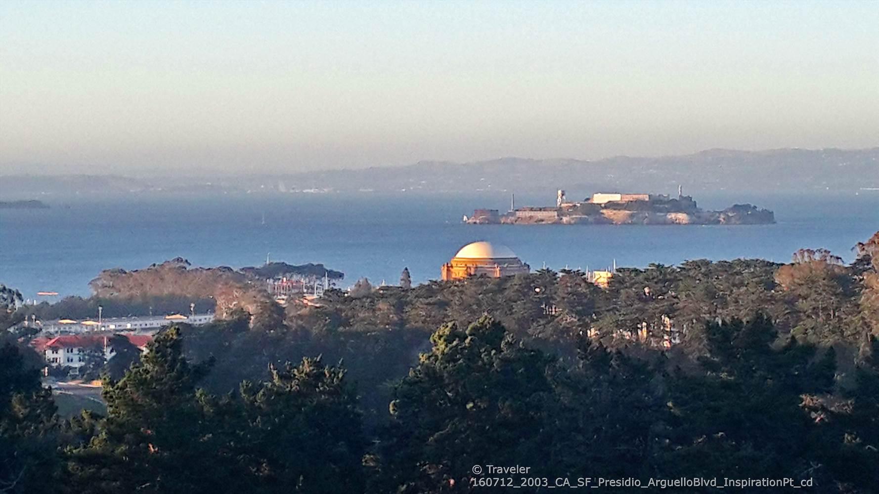 Distant island in a bay, with a dome and trees in the foreground.
