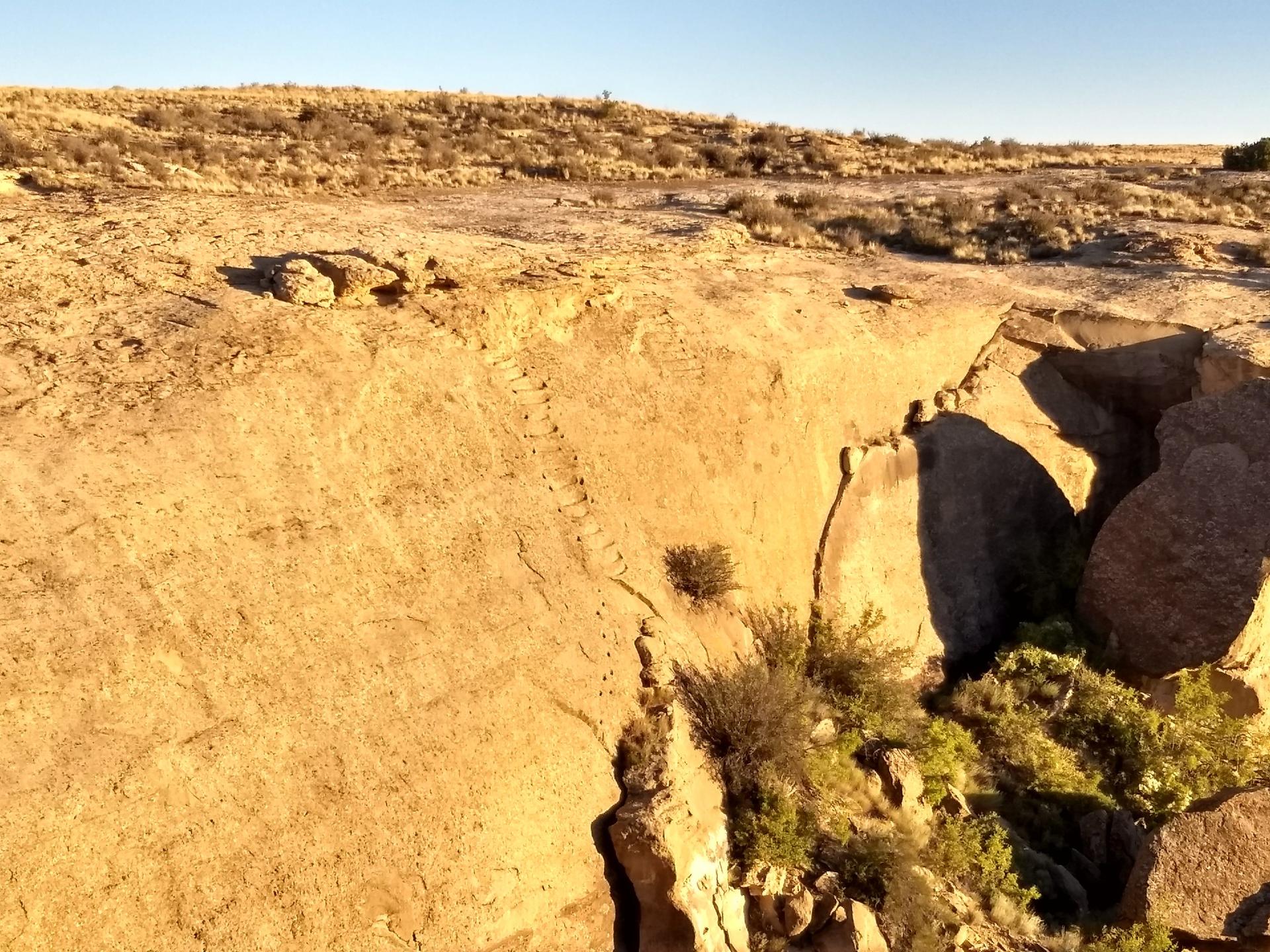 Close-up of a deep crack in a large, sunlit rock formation in a desert.