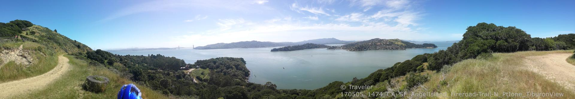 Panoramic view of a calm bay, distant hills, and a winding dirt path.