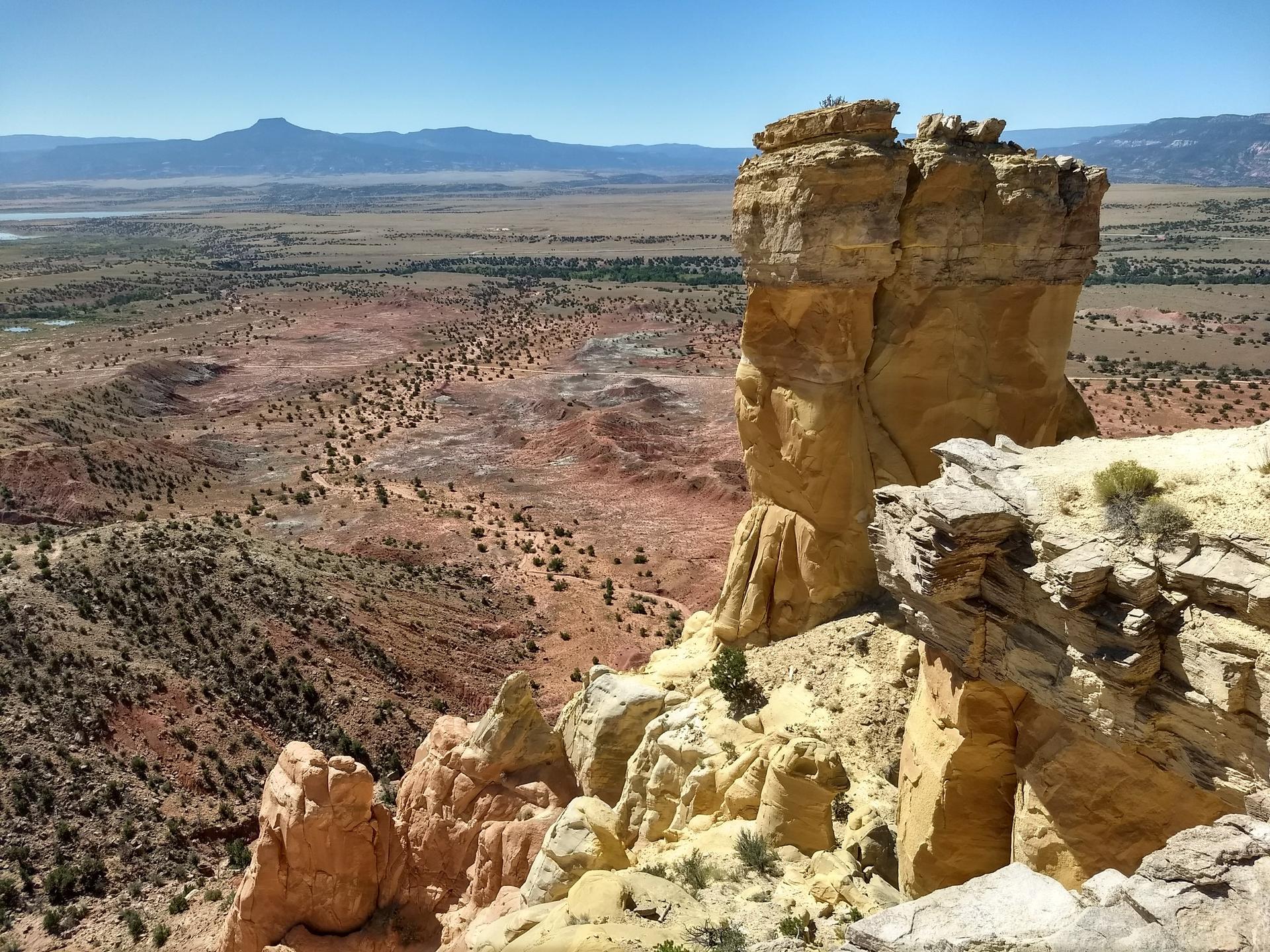 A towering rock formation overlooks a vast, rugged desert expanse.