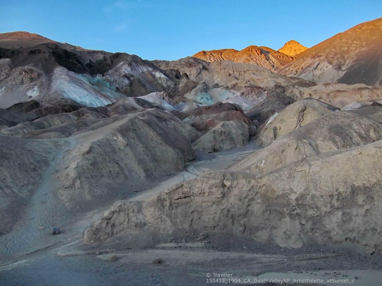 Rugged, colorful desert mountains with some peaks illuminated by golden light.
