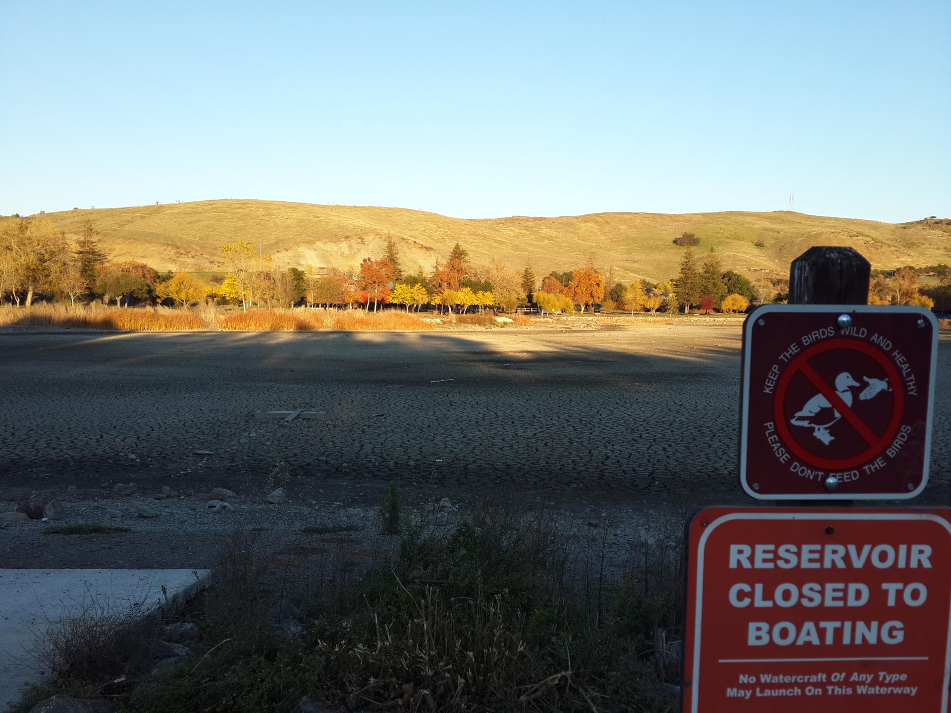 Dry lakebed under golden light with warning signs in foreground.