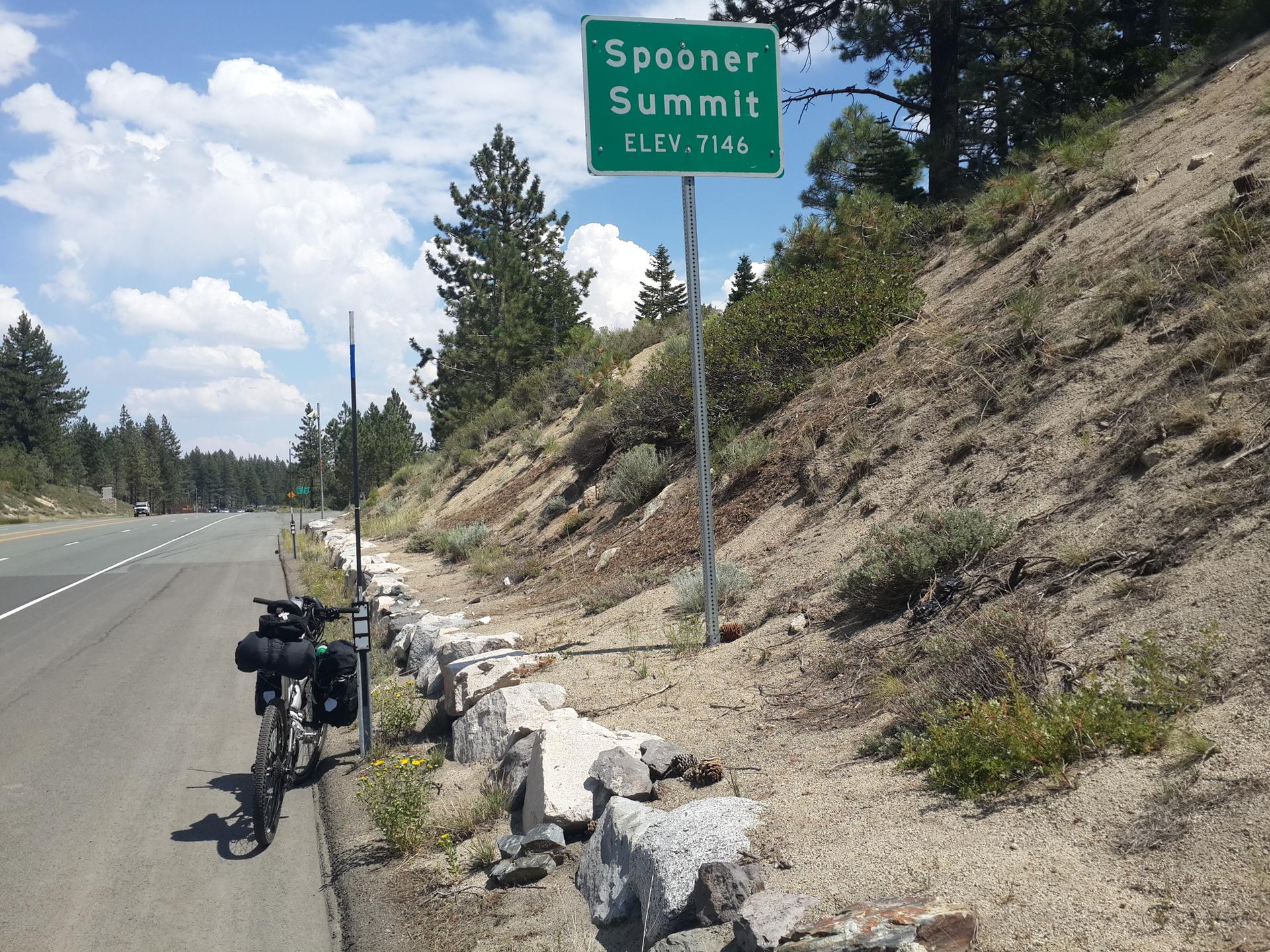A touring bicycle is parked beside a highway sign on a sunny day.