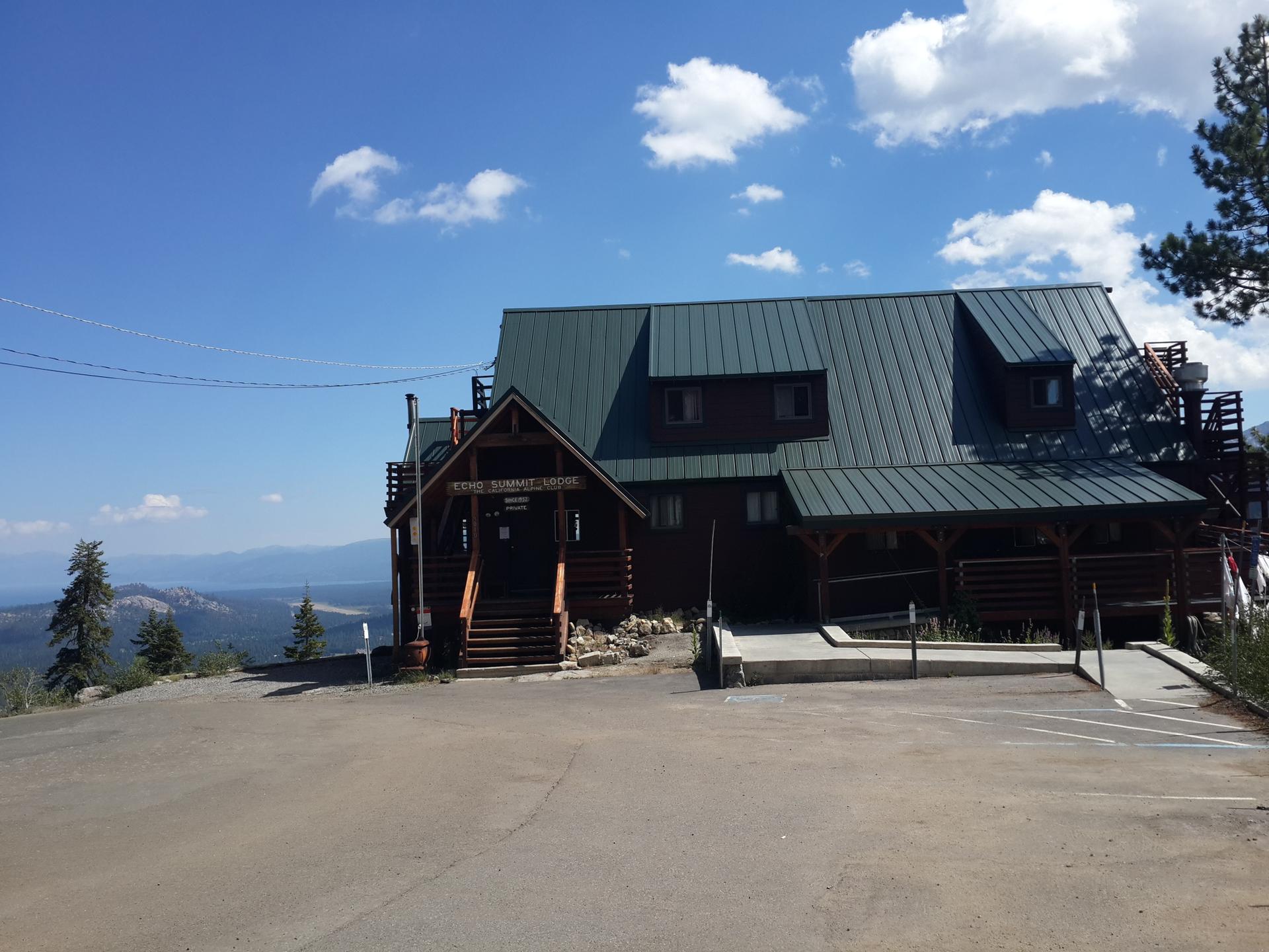 Large lodge building with a green roof under a bright blue sky.
