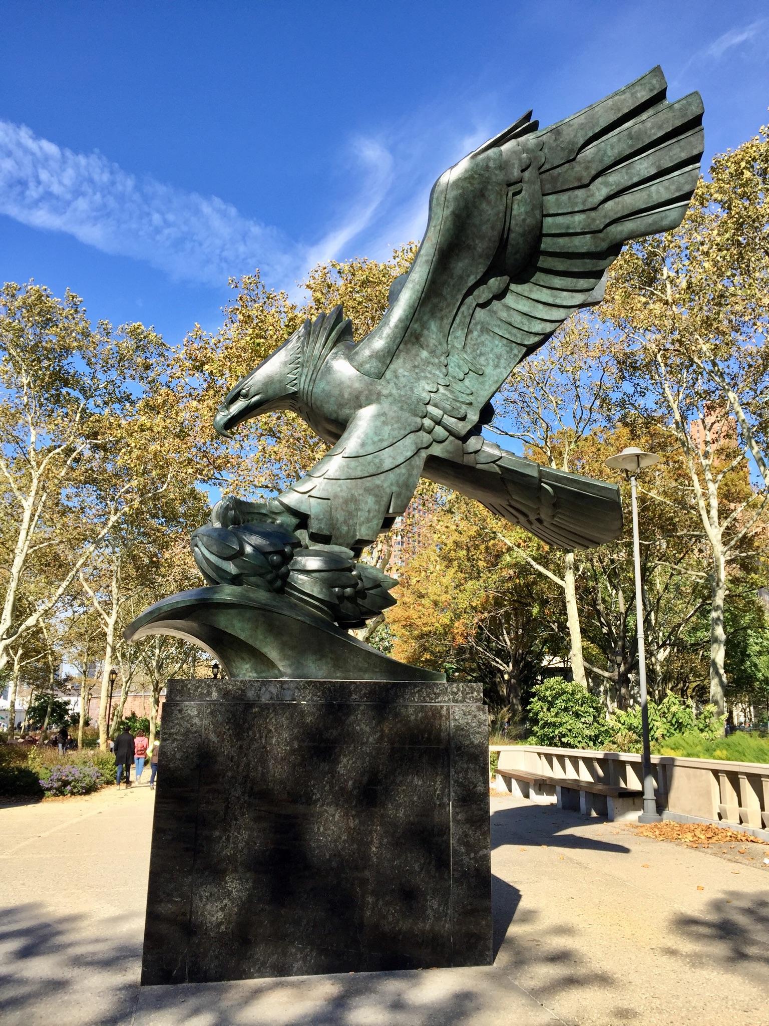 Large bronze eagle statue with outstretched wings against a blue sky.