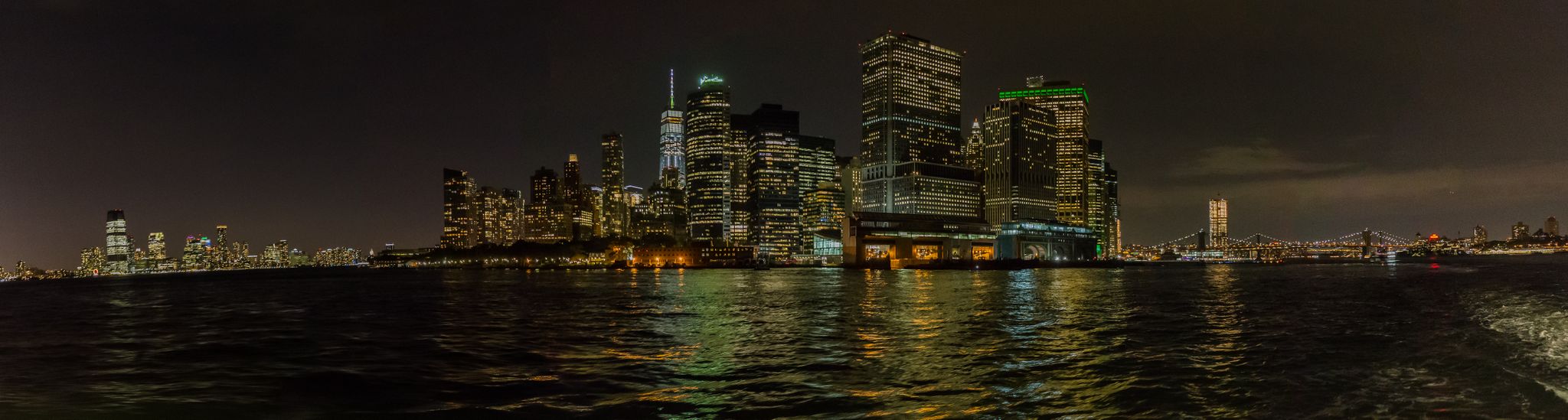 Night panorama of a brightly lit city skyline reflecting on dark water. - Manhattan Waterfront Greenway