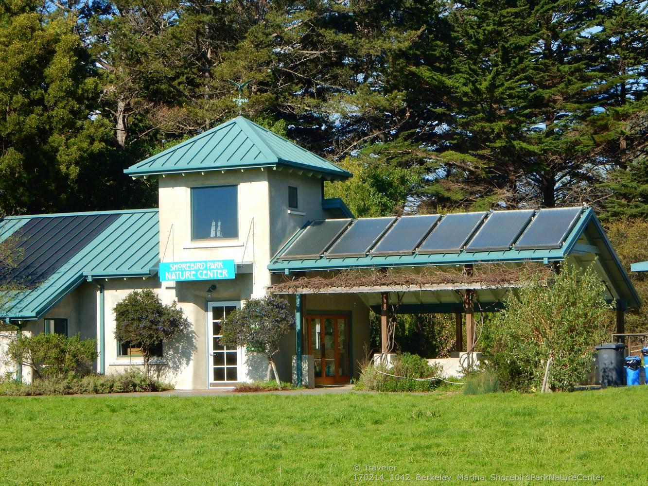 A building with solar panels and a green roof, surrounded by trees and grass.