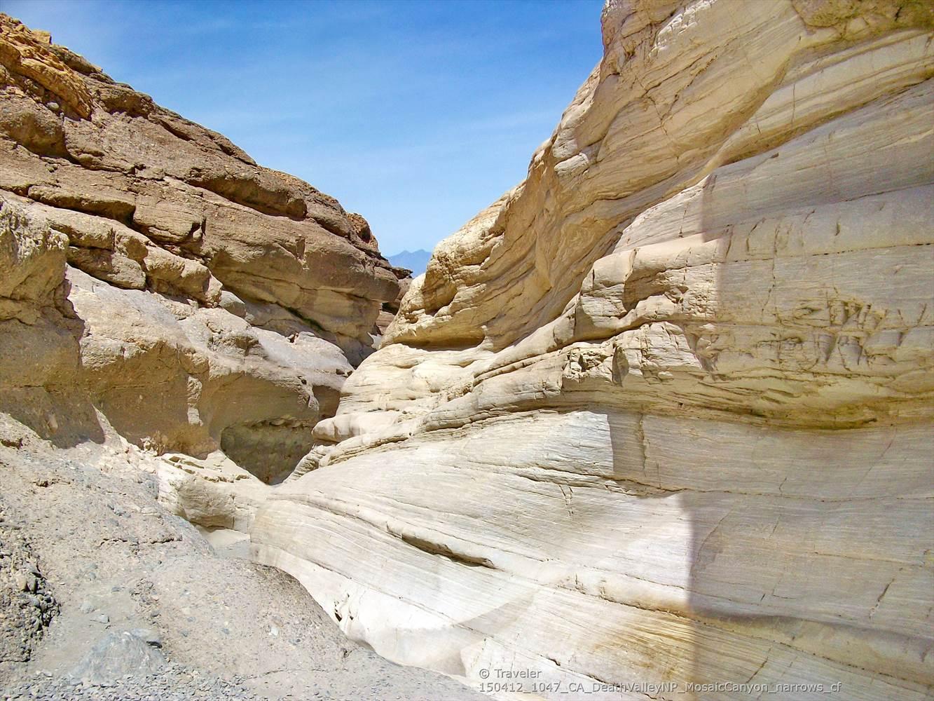 Sunlight illuminates smooth, layered rock walls inside a narrow slot canyon.