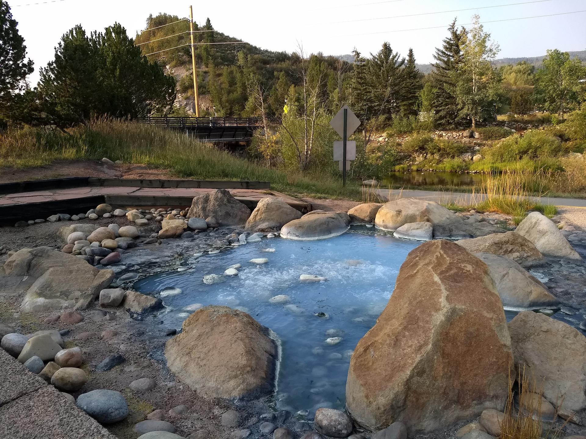 A light blue natural pool surrounded by rocks under bright daylight.