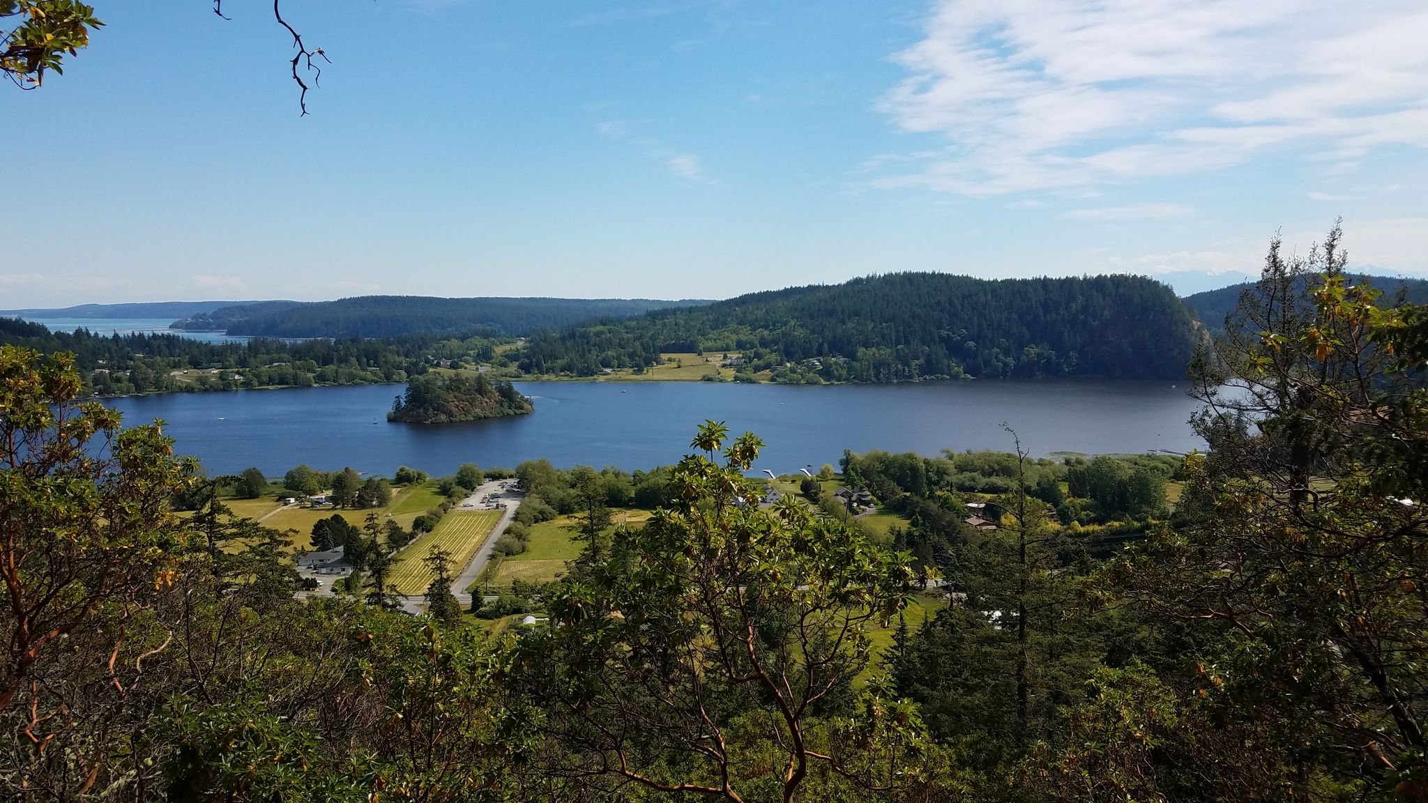 Panoramic view of a large lake with an island, surrounded by green hills. - Mount Erie & Sugarloaf loop