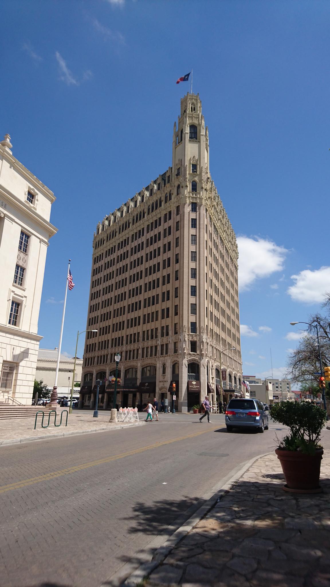 A tall, ornate building with a spire under a bright blue sky.