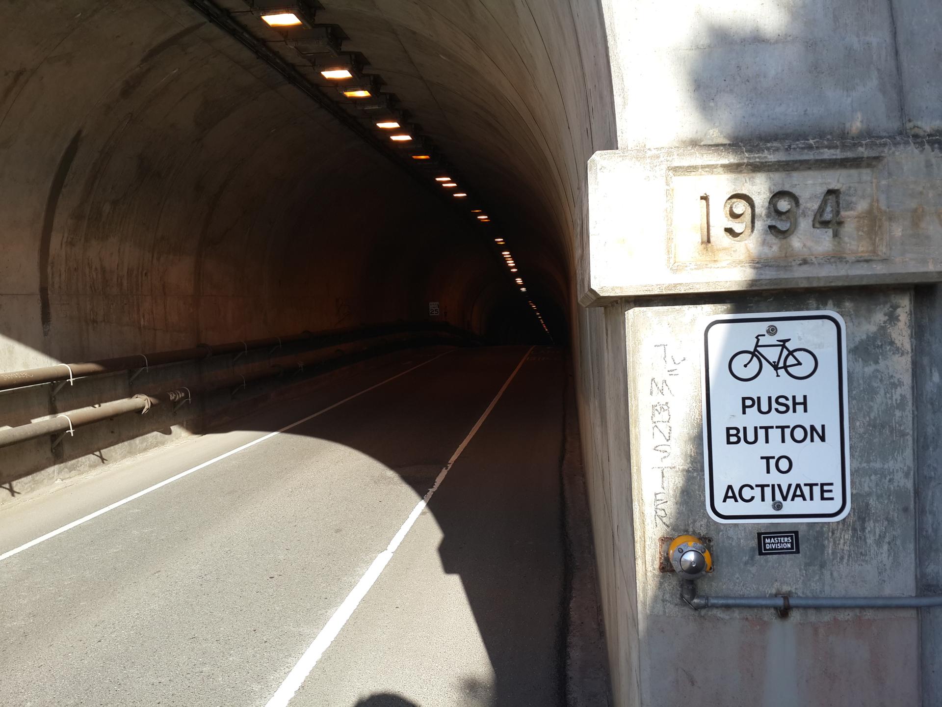 A dark tunnel entrance with a 'Push Button to Activate' sign.