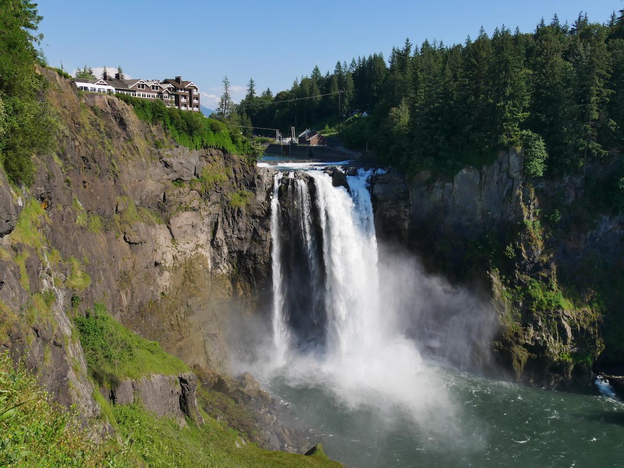Bright sunny view of a powerful waterfall cascading down rocky cliffs.