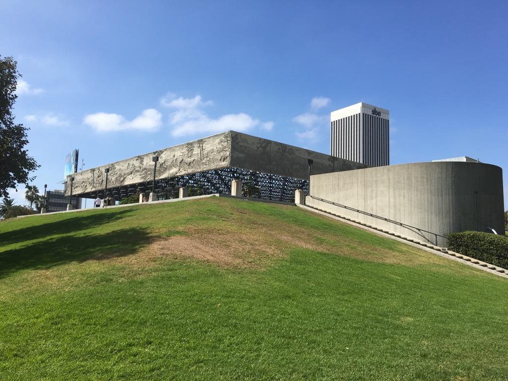 Modern concrete building on a green grassy hill under a clear blue sky.