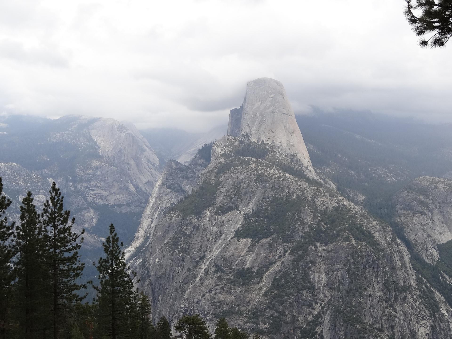 A large dome-shaped mountain peak rises above misty, forested slopes.