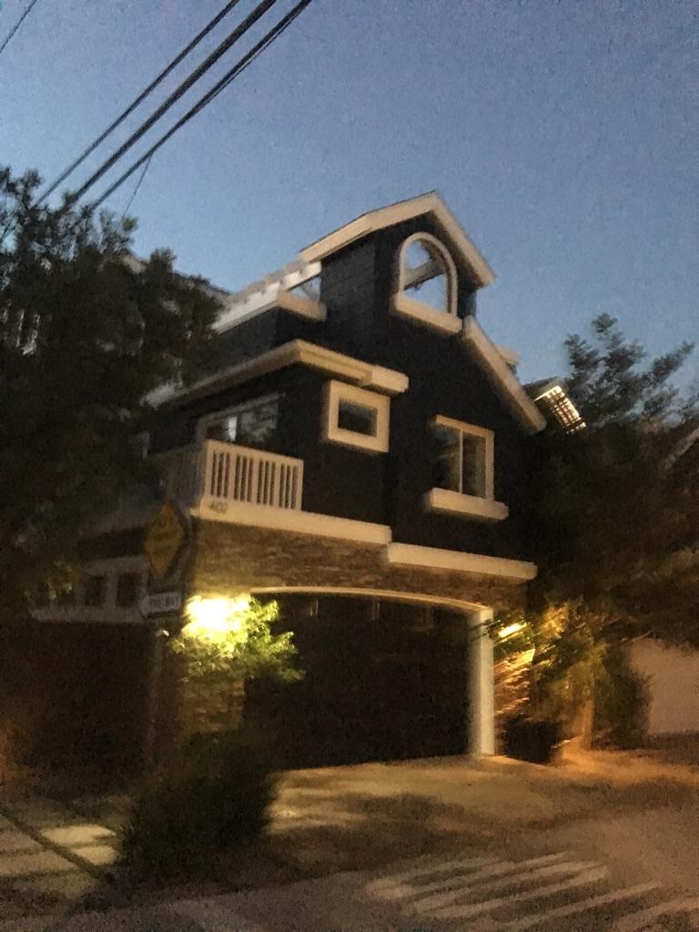 Dark house with illuminated windows at dusk, surrounded by trees.