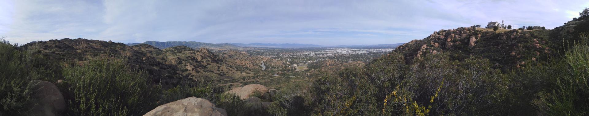 Panoramic view of a sprawling city in a valley surrounded by green hills.