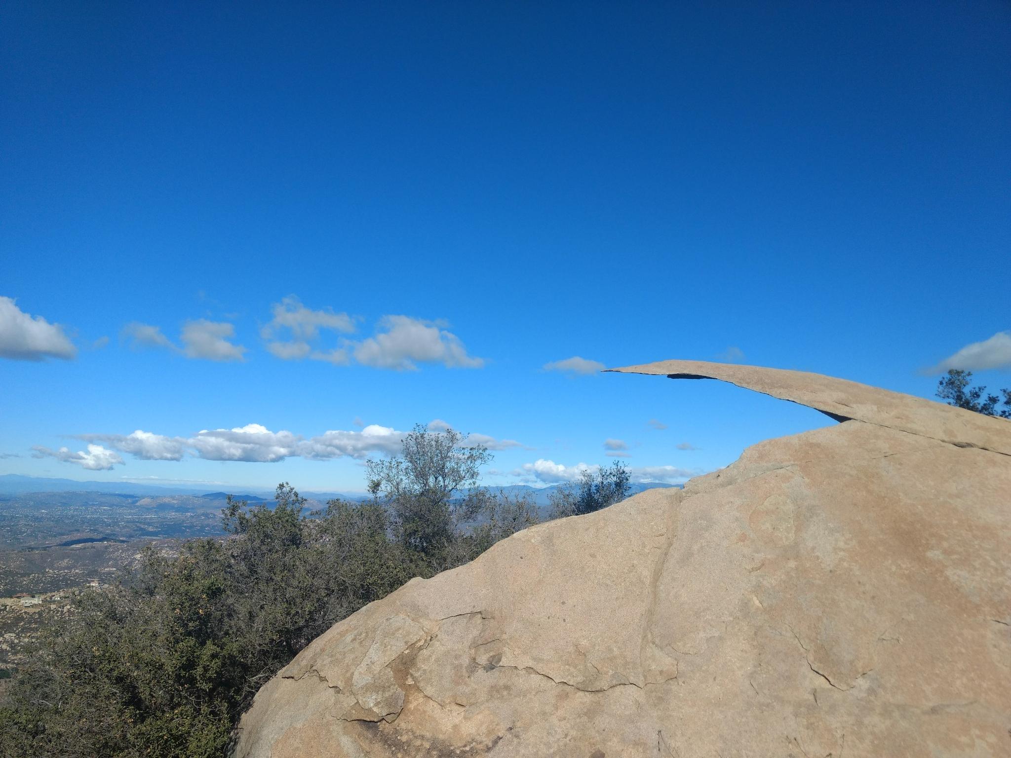 Unique rock formation resembling a thin slab against a blue sky.